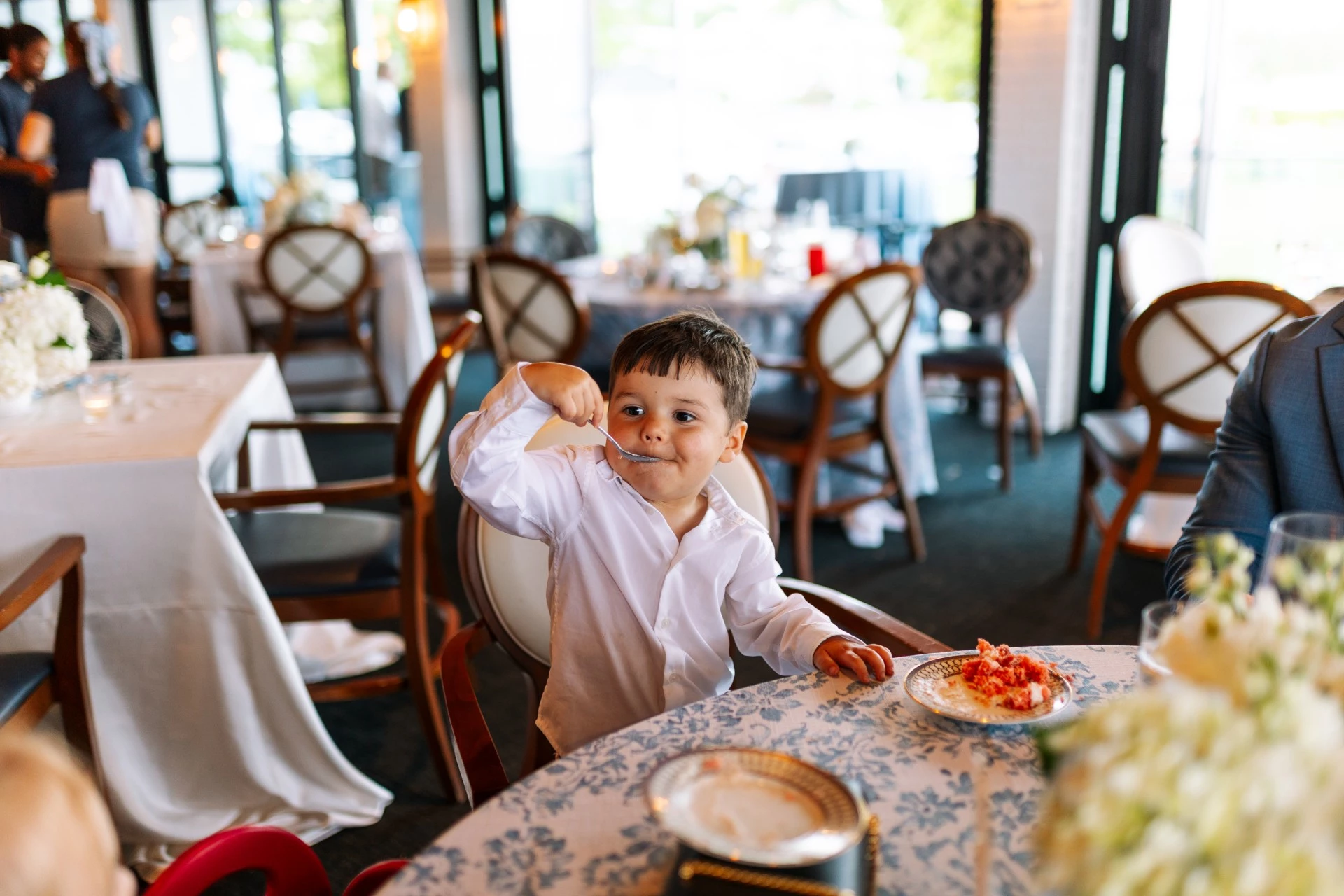 Young boy flexing his arm at a table during a wedding reception