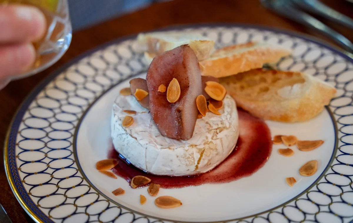 Baked brie topped with poached pear and toasted almonds, served with crostini