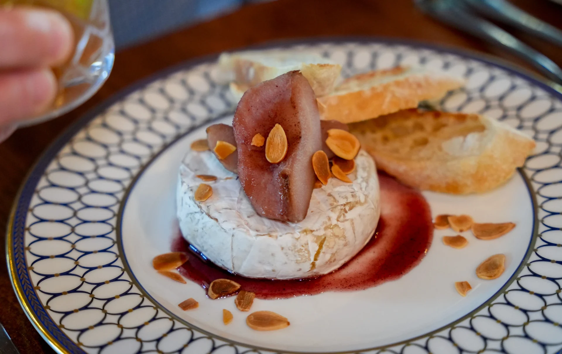 Baked brie topped with poached pear and toasted almonds, served with crostini