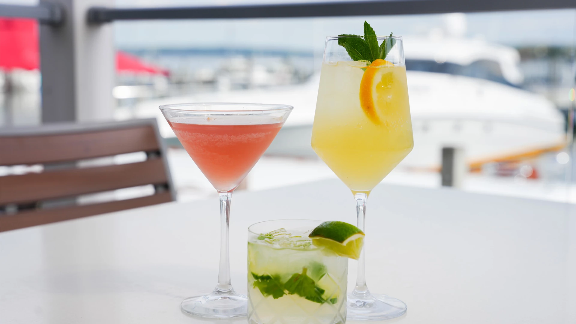 Three cocktails on a deck table overlooking the marina