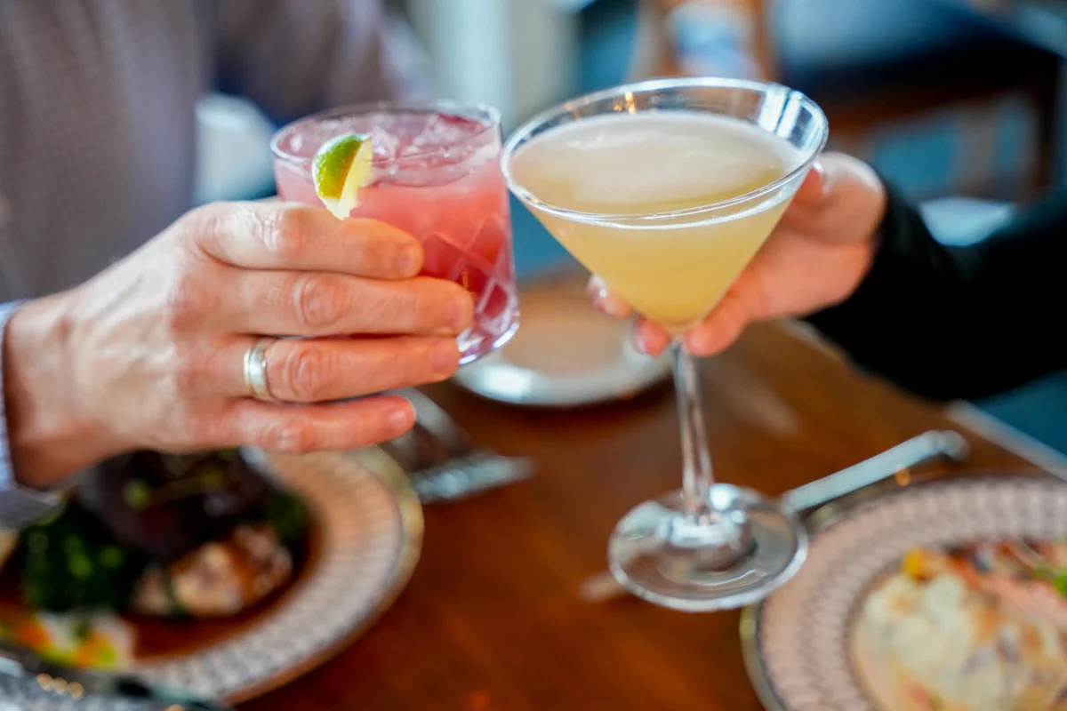 Two guests toasting cocktails over dinner