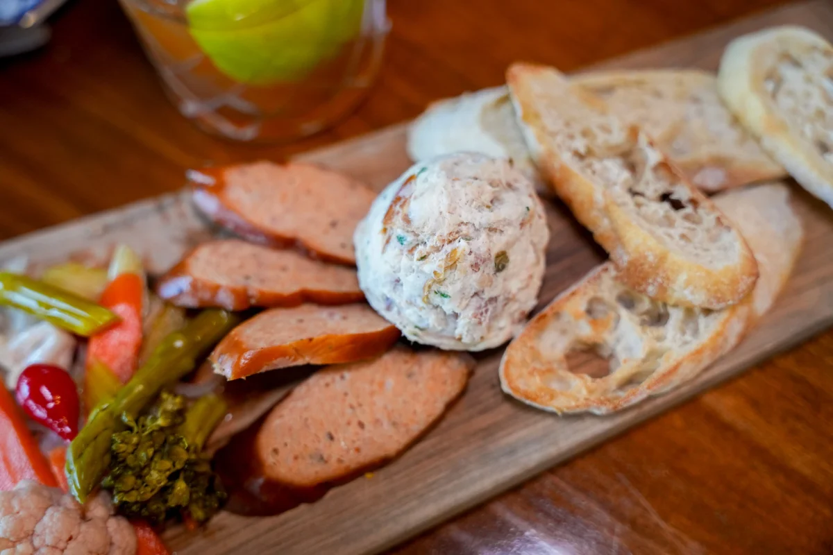 Charcuterie board with sliced sausage, pate, pickled vegetables and crostini
